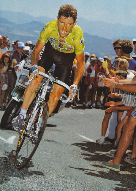 A grimacing man in a lime green jersey cycles up a mountain