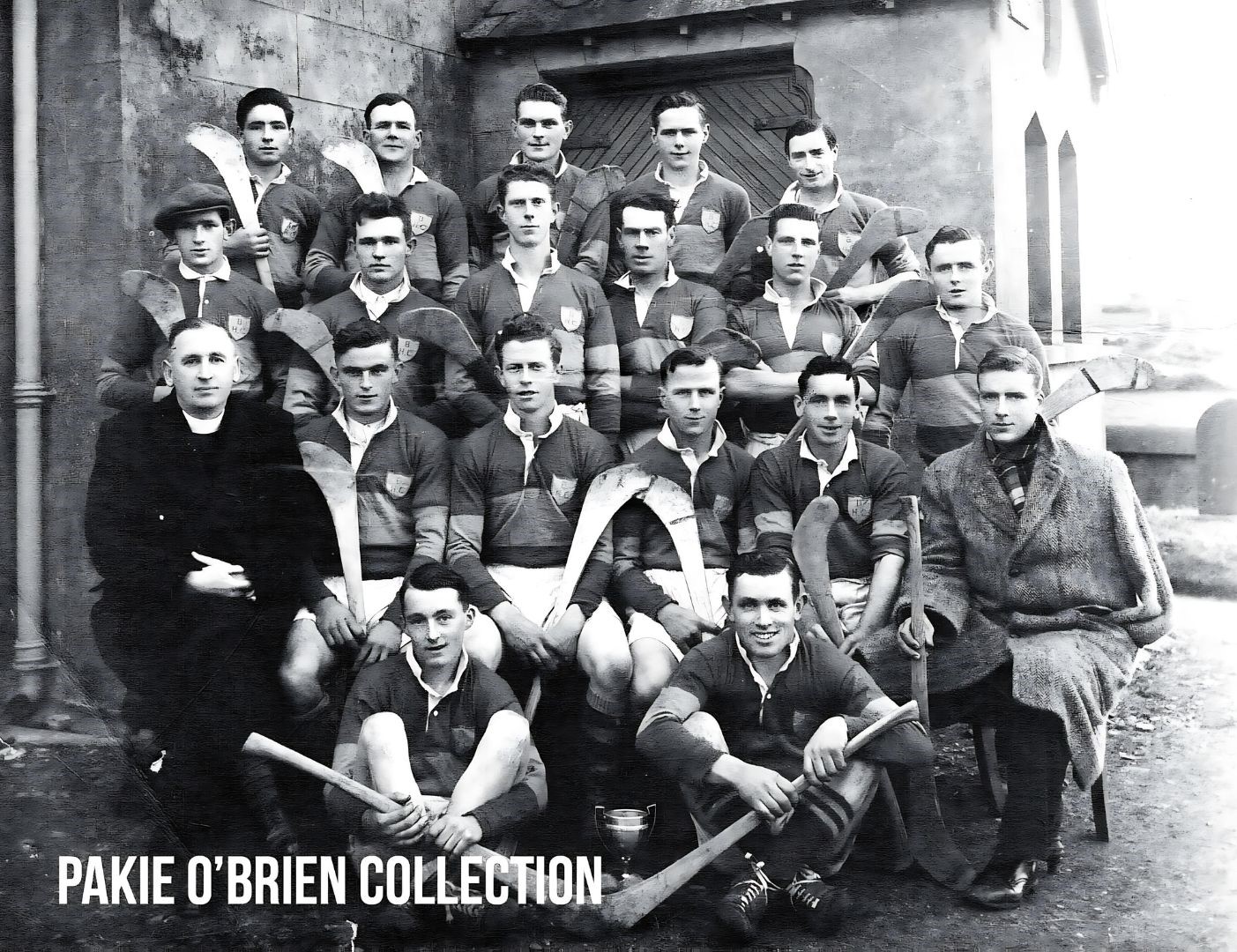 Black & white photo of an old hurling team and a priest