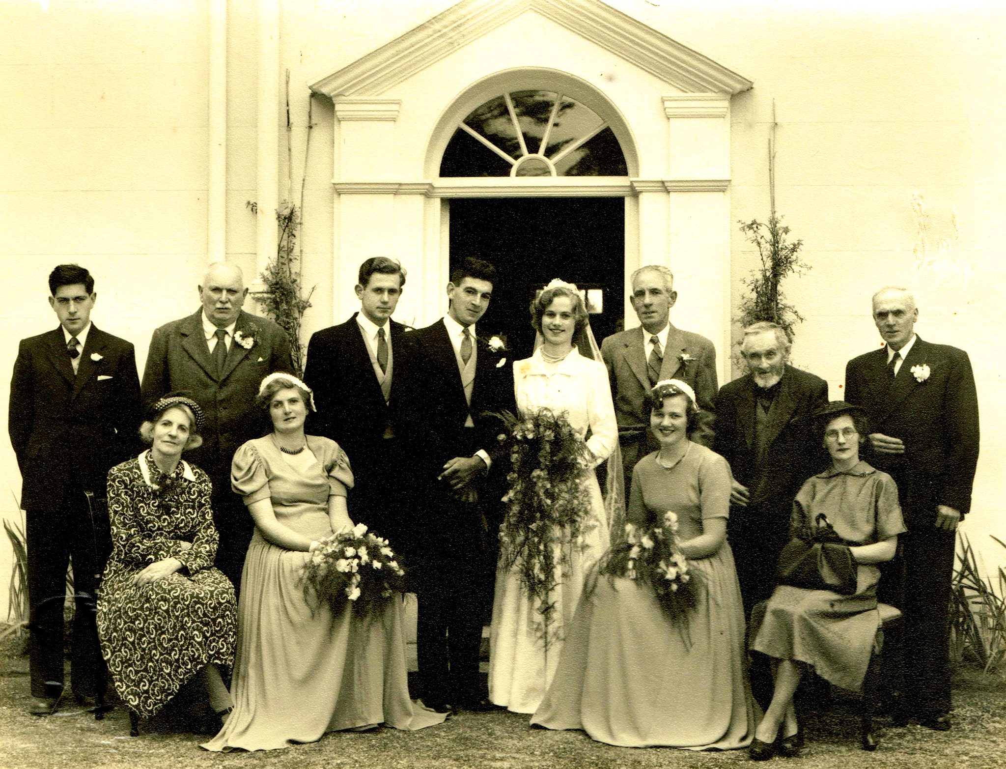 Black & white photo of a family wedding group, including the bride and groom.