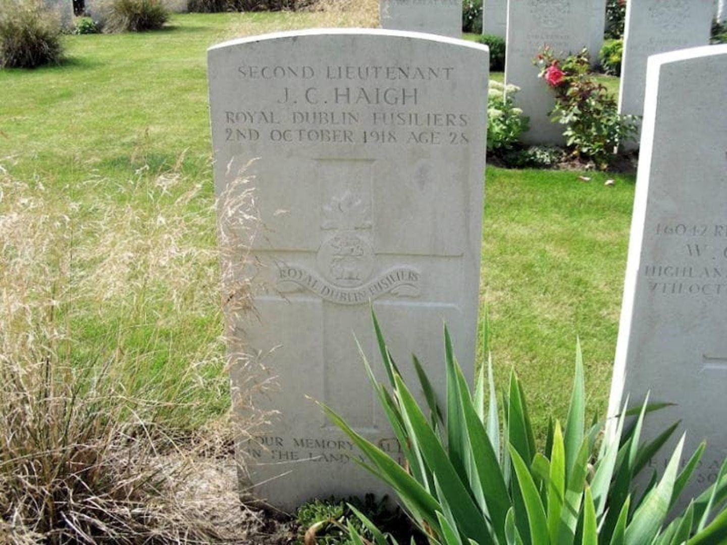 Colour photograph of a Grave headstone with grass around it.